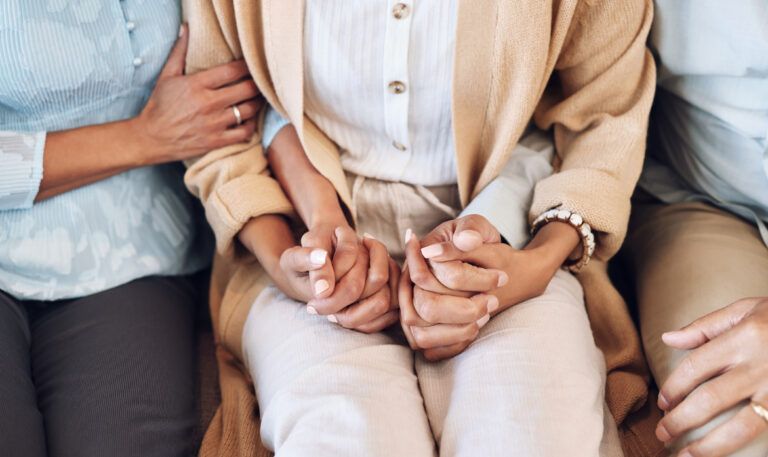 Tres personas cogidas de las manos de la persona del medio
